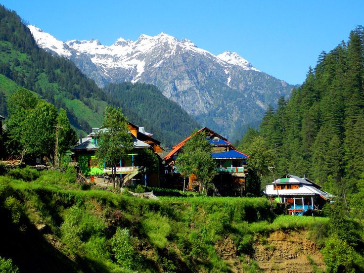 the mountains are covered in snow and green grass, while houses sit on top of each other