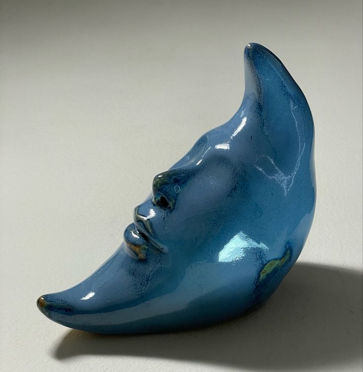 a blue vase with a face shaped like a human's head on the table