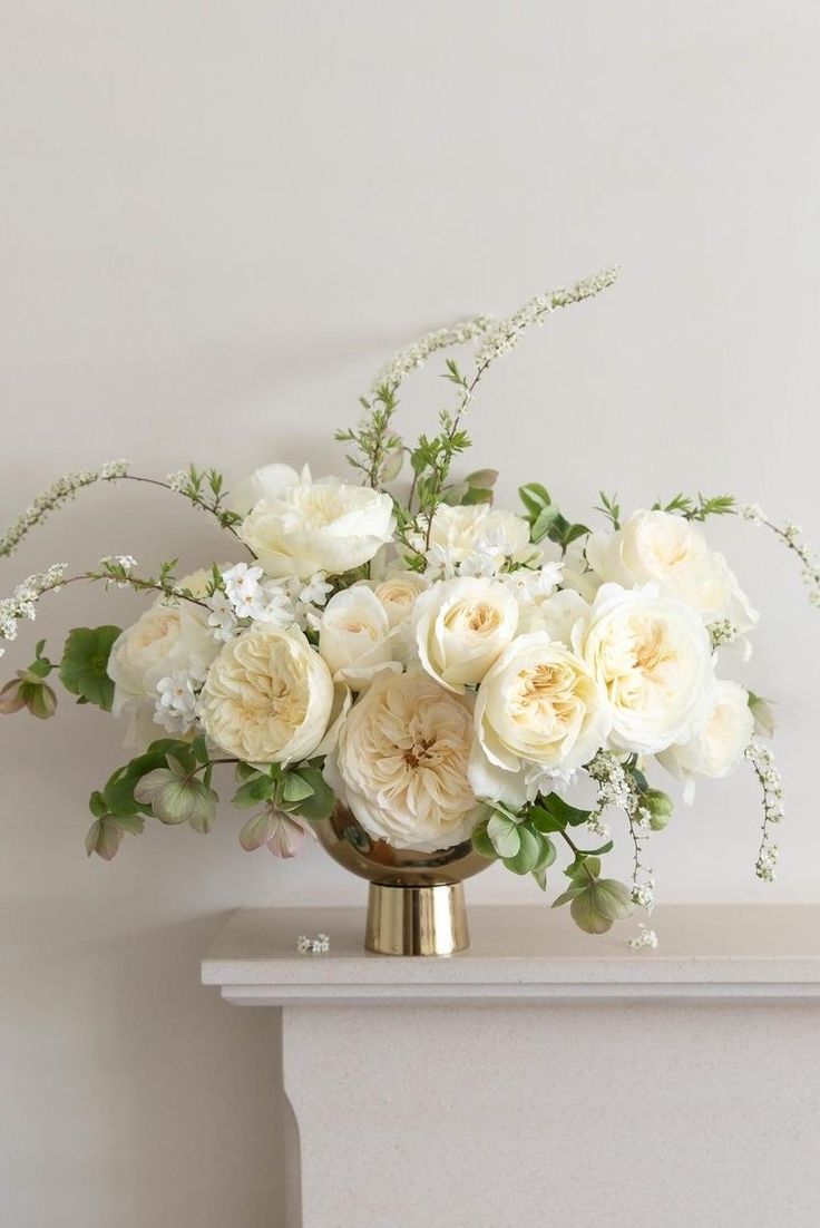 a vase filled with white flowers on top of a mantle