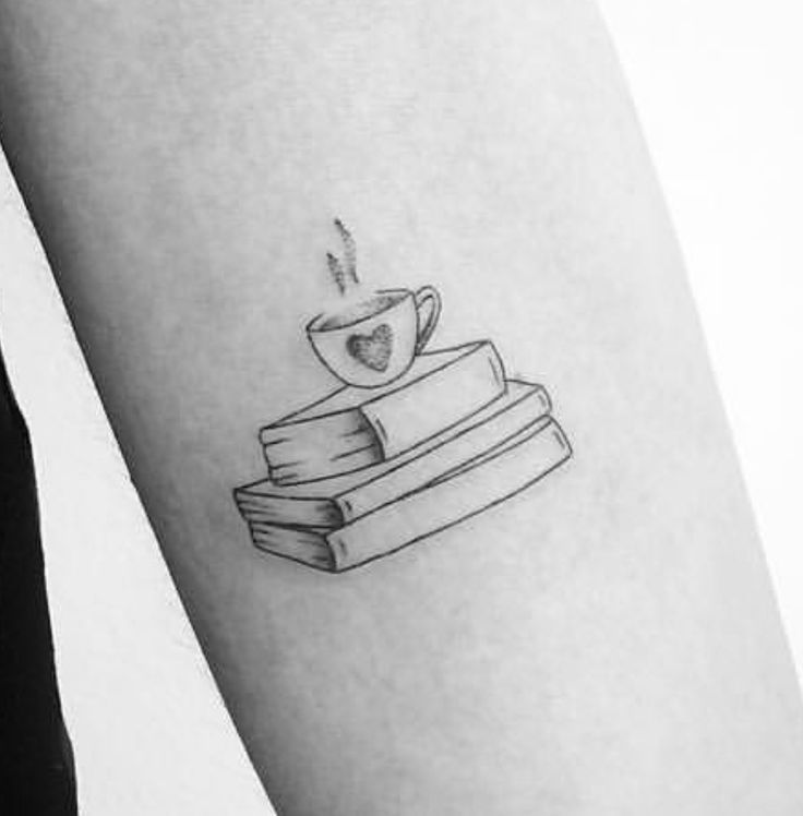 a cup of coffee and books tattoo on the left inner arm, with a heart in it