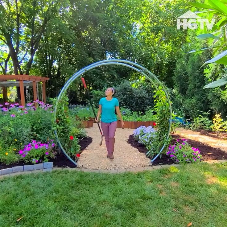 a woman standing in the middle of a garden with a circular mirror on it's side