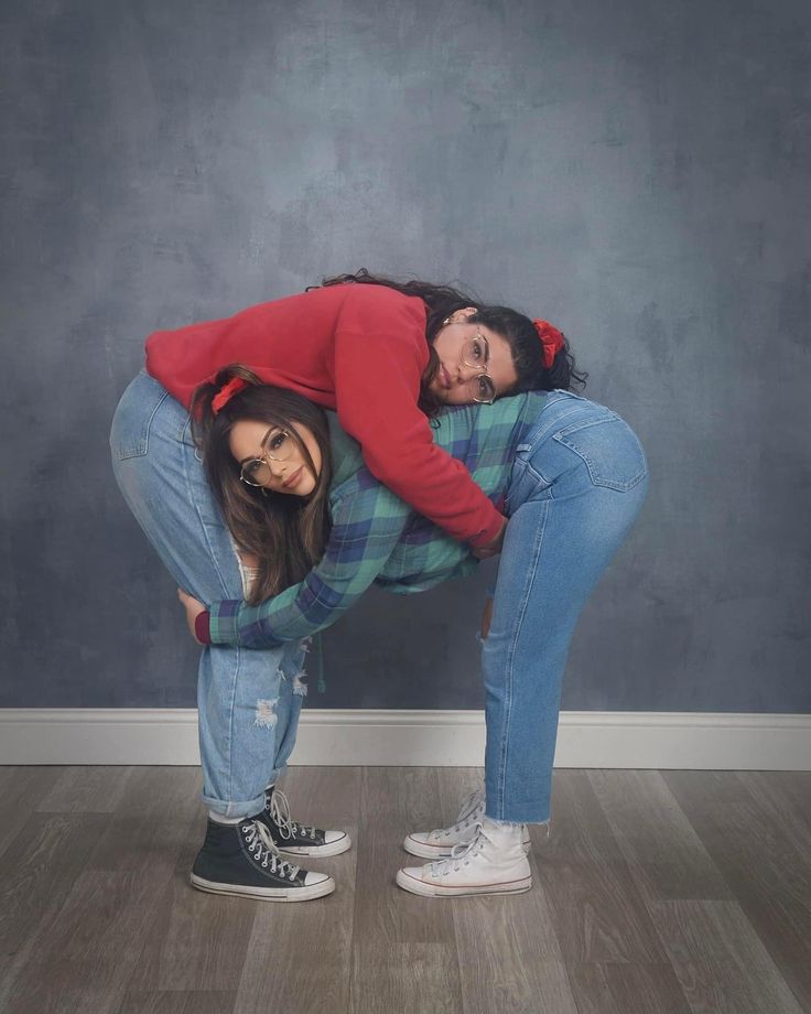 two women in jeans and red sweaters are posing for a photo with their arms around each other