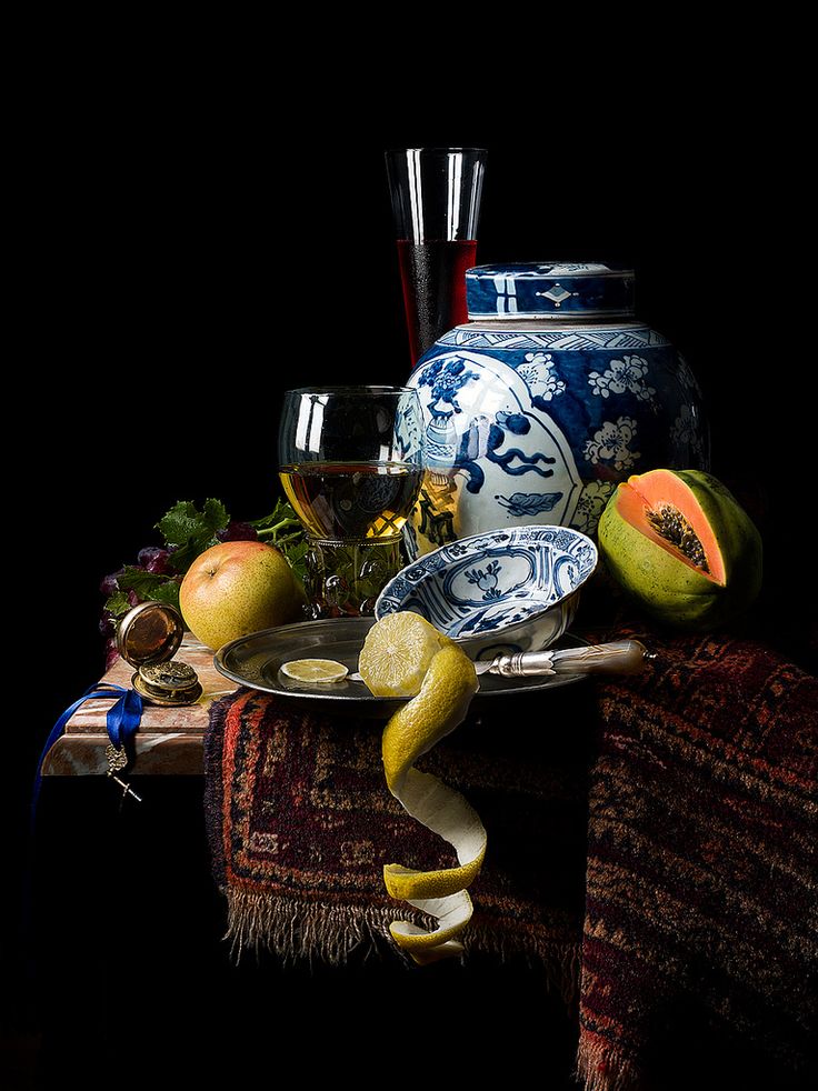 a table topped with plates and bowls covered in fruit next to a vase filled with water