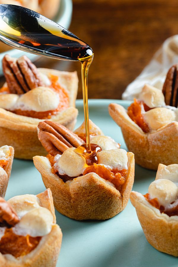 a spoon drizzling caramel sauce onto mini pies on a plate