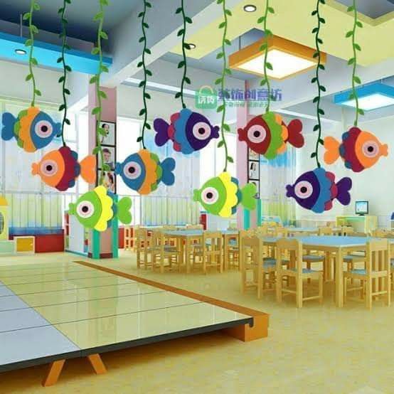 a room with tables, chairs and colorful fish decorations hanging from it's ceiling