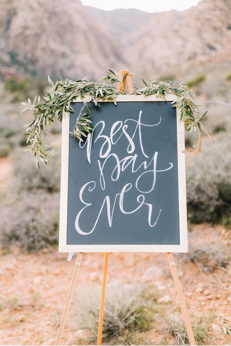 a chalkboard sign with the words best day ever written on it in front of mountains