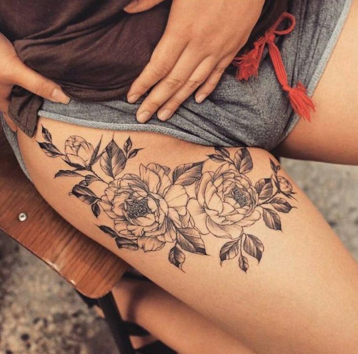 a woman's thigh with flowers and leaves on the side, as well as her legs