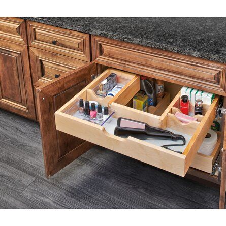 an open drawer in the middle of a kitchen counter with nail polish and other items