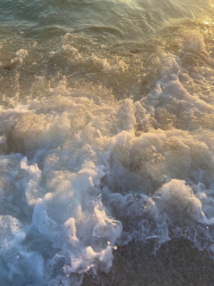 the surf is crashing on the beach and it's foamy water looks like waves