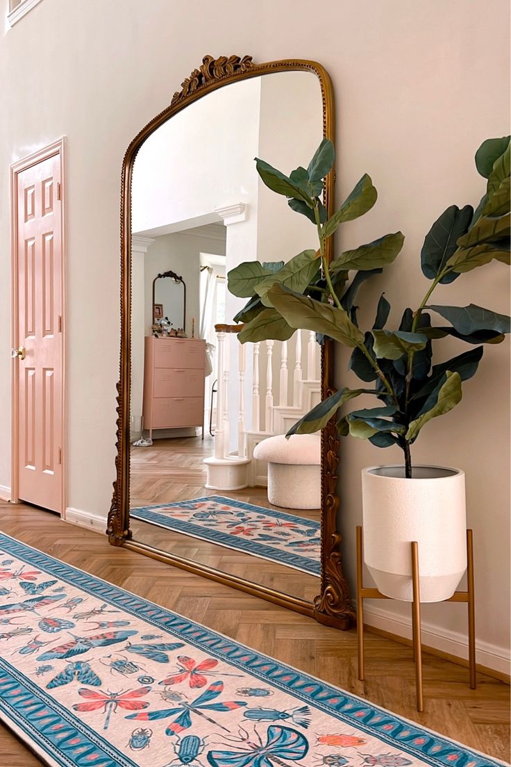 a large mirror sitting on top of a wooden floor next to a potted plant