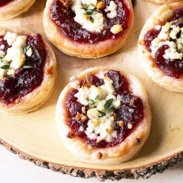 mini pizzas with cheese and cranberry sauce on a wooden platter, ready to be eaten