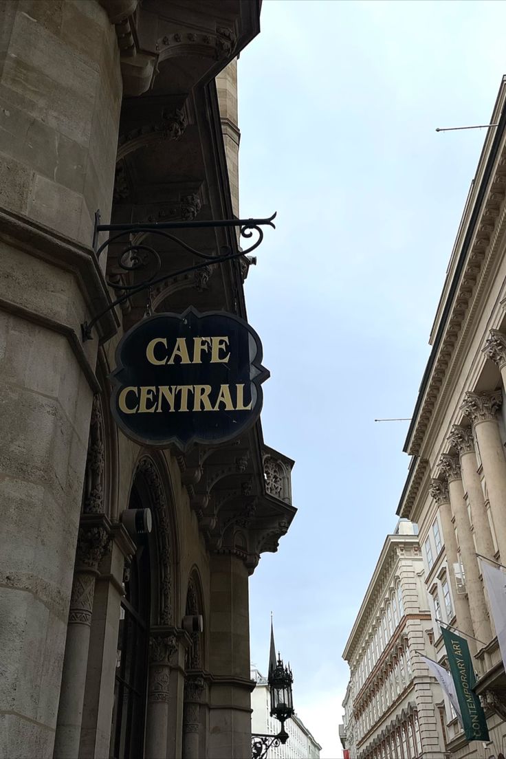 there is a sign that says cafe central hanging from the side of a tall building