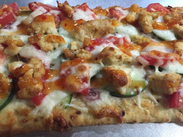 a close up of a pizza with chicken and veggies on it's crust