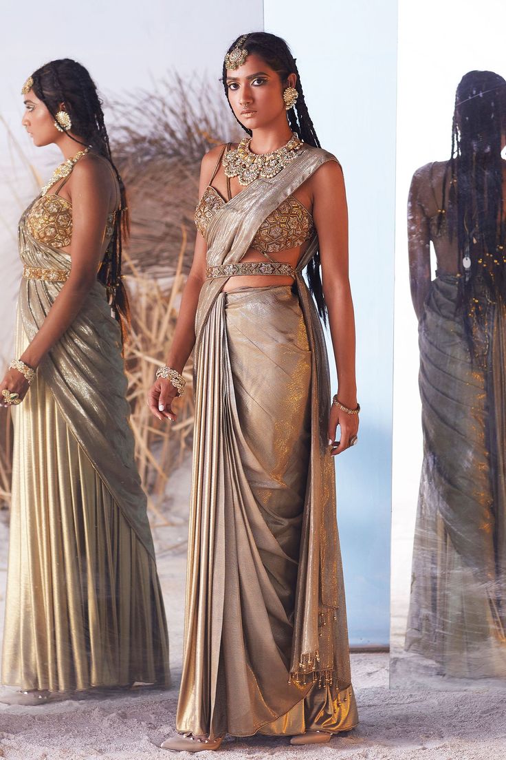 Metallic draped lehenga saree with embroidered patchwork at shoulder with gold tassels on pallu hem.  Paired with embellished strappy blouse with strings attached at the bottom and embroidered belt.
Components:3
Pattern:Embroidered
Neckline:Plunge Neck
Sleeve Length:Sleeveless
Fabric:Modal Satin, Lurex, Lycra
Color:Gold
Other Details:
Tassel detail
Midriff tie-ups
Pleated saree bottom
Star motif shoulder patch
Occasion:Reception - Aza Fashions Spaghetti Blouse, Drape Lehenga, Saree Pallu, Pleated Saree, Saree And Blouse, Star Motif, Lehenga Saree, Stylish Pants, Embroidered Neckline