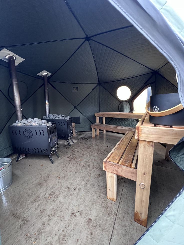 the inside of a tent with benches and stoves