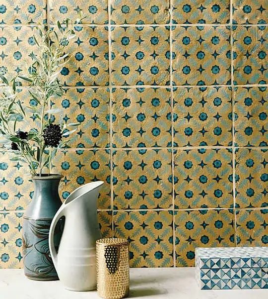 two vases sitting on a counter next to a wall with blue and yellow tiles