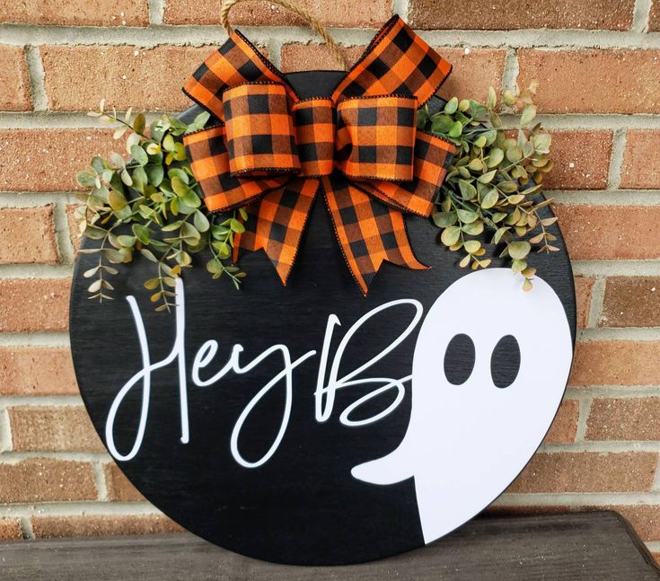 a black and orange door hanger with a ghost on it's side that says hey