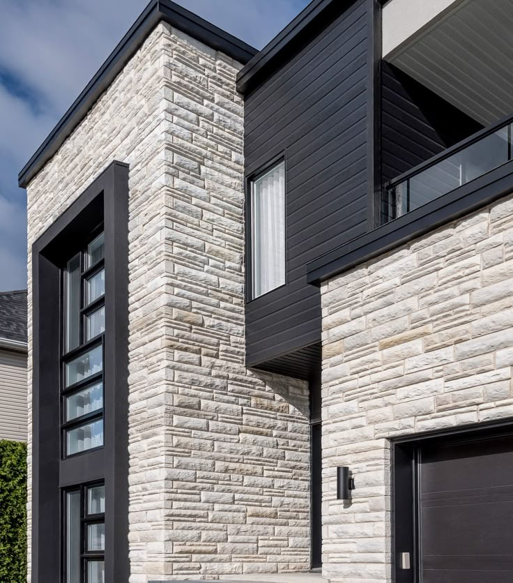 two garage doors are open in front of a brick and stone building with black shutters