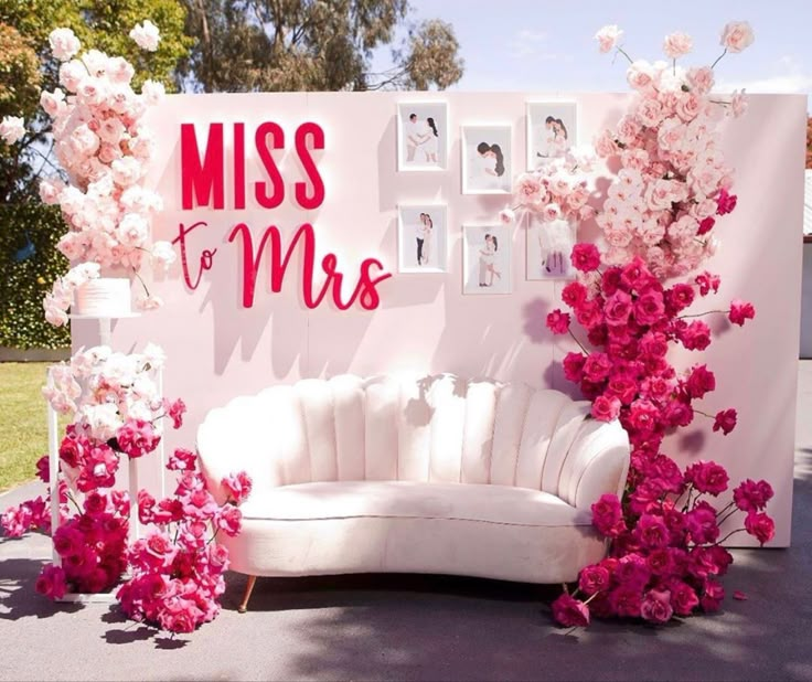 a white couch sitting next to a wall with pink flowers on it and a sign that says miss to mrs