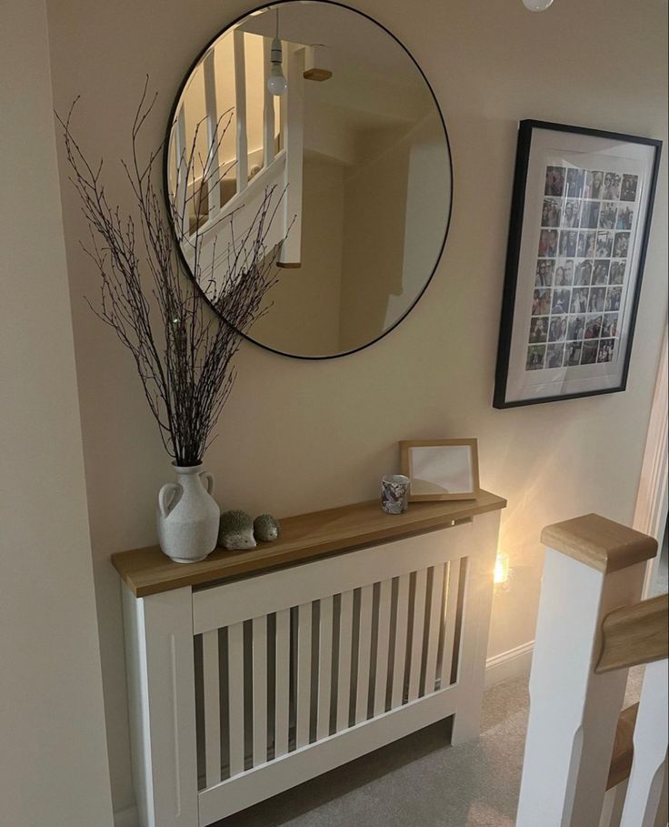 there is a mirror on the wall above a radiator and a vase with branches in it