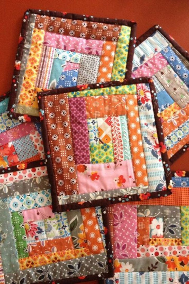 a pile of colorful patchwork quilts sitting on top of a red tablecloth