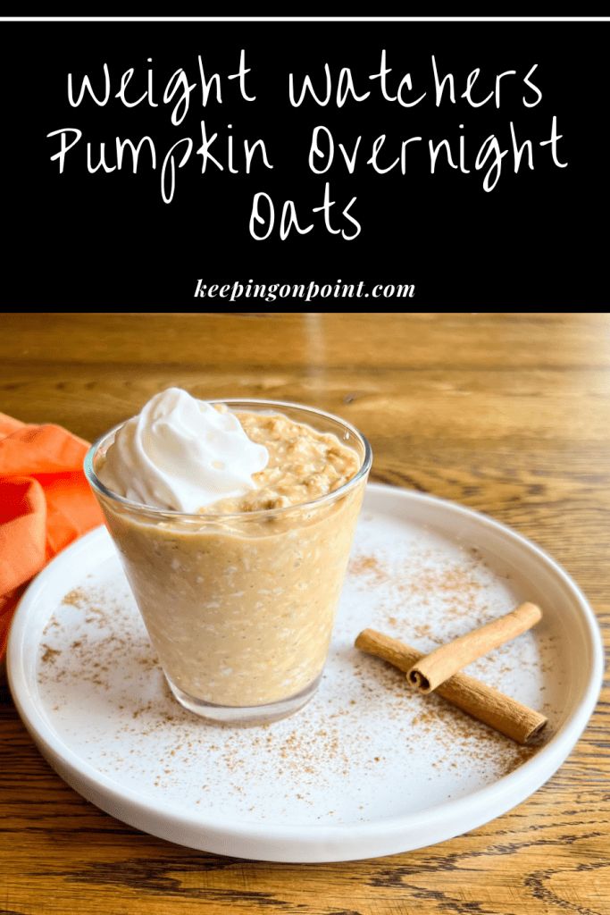 pumpkin overnight oatmeal with cinnamon sticks and whipped cream in a glass on a white plate