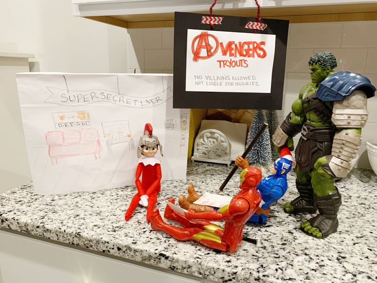 some toys are sitting on a counter top in front of a sign that says avengers