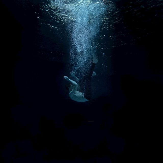 a man swimming under water in the dark