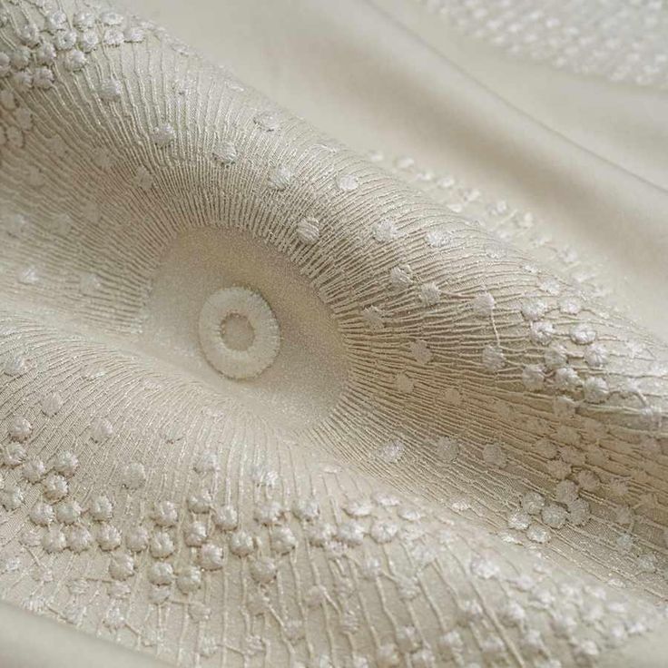 close up view of white fabric with an intricate design on the bottom and side of it