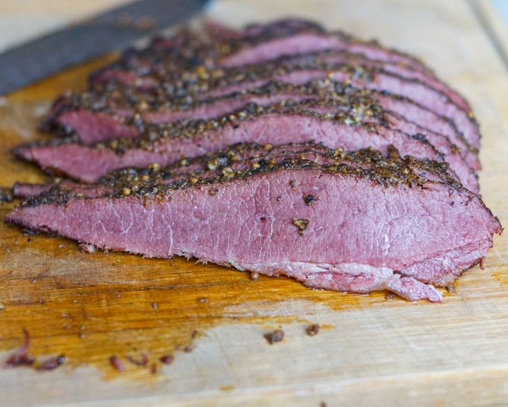 sliced meat sitting on top of a wooden cutting board