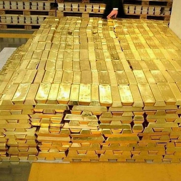 a man standing next to stacks of gold bars