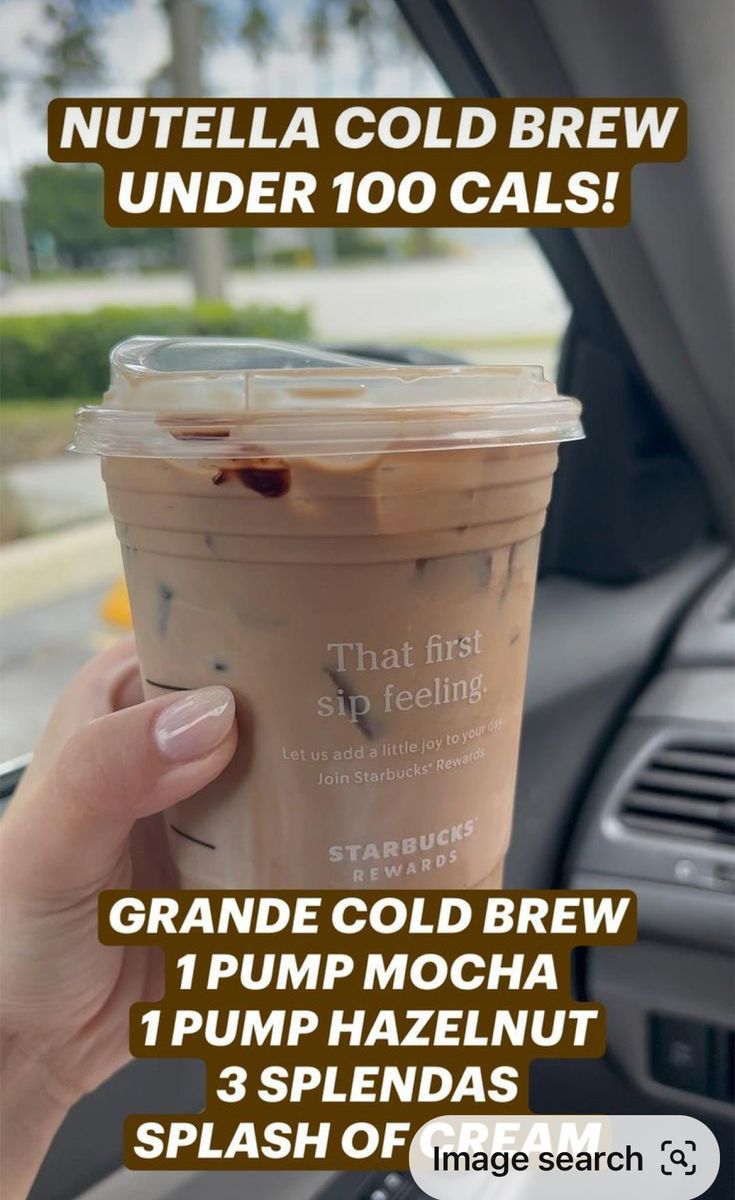 a woman holding up a cup of coffee in her car