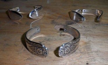 two silver bracelets sitting on top of a wooden table