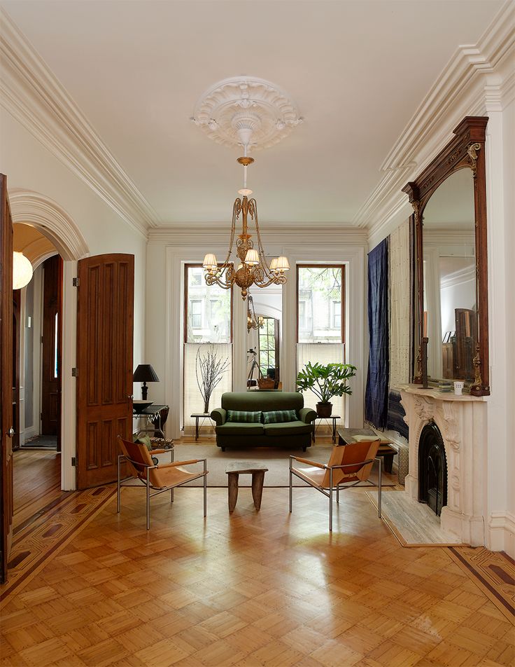 a living room filled with furniture and a chandelier hanging from the ceiling over a fire place