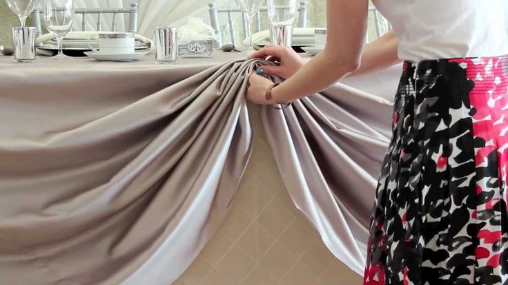 a woman standing in front of a table with a curtain on it's side