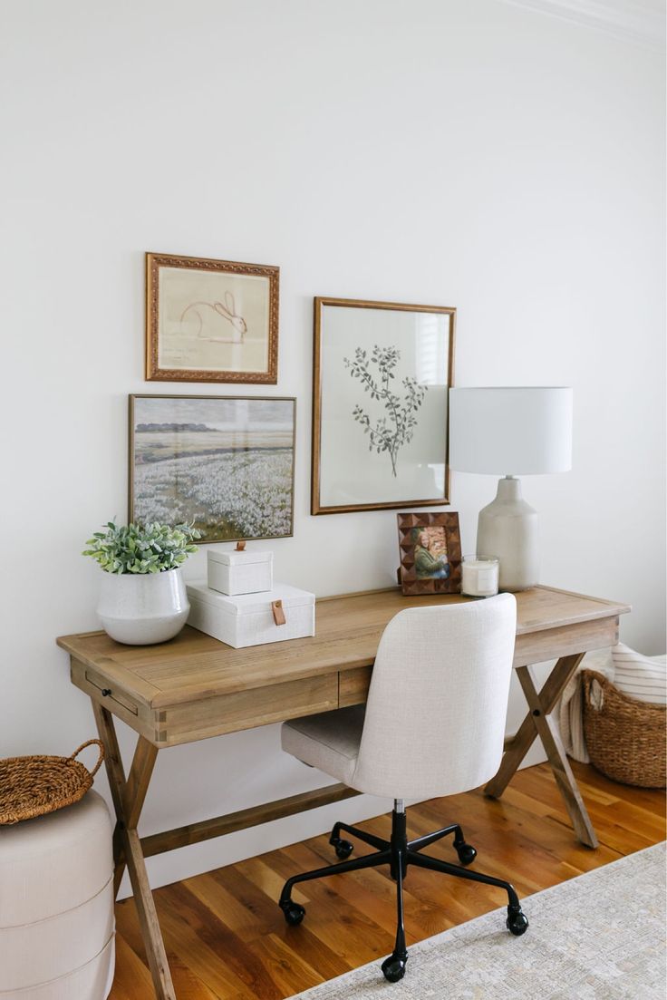 a white chair sitting next to a desk with pictures on the wall above it and a lamp