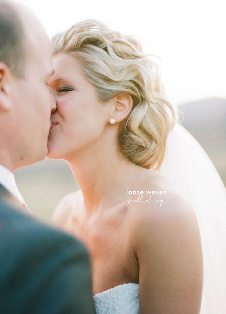 a bride and groom kissing each other outside