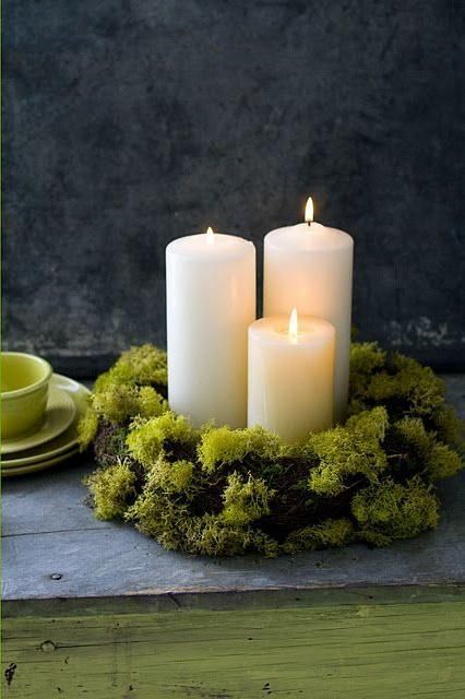 three white candles sitting on top of a table next to a green bowl and plate