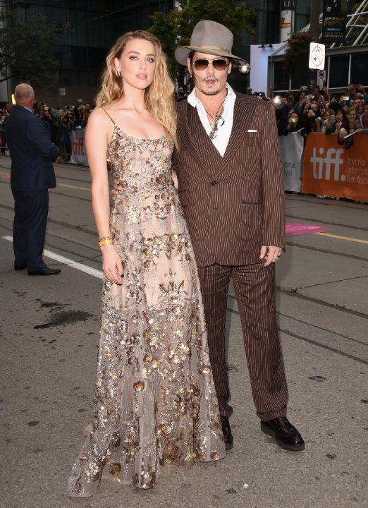 two people standing next to each other in front of a crowd at a red carpet event