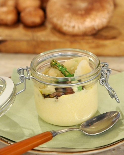 a glass jar filled with food sitting on top of a plate next to a spoon