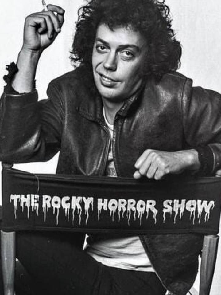 a black and white photo of a man sitting in a chair with the rocky horror show sign