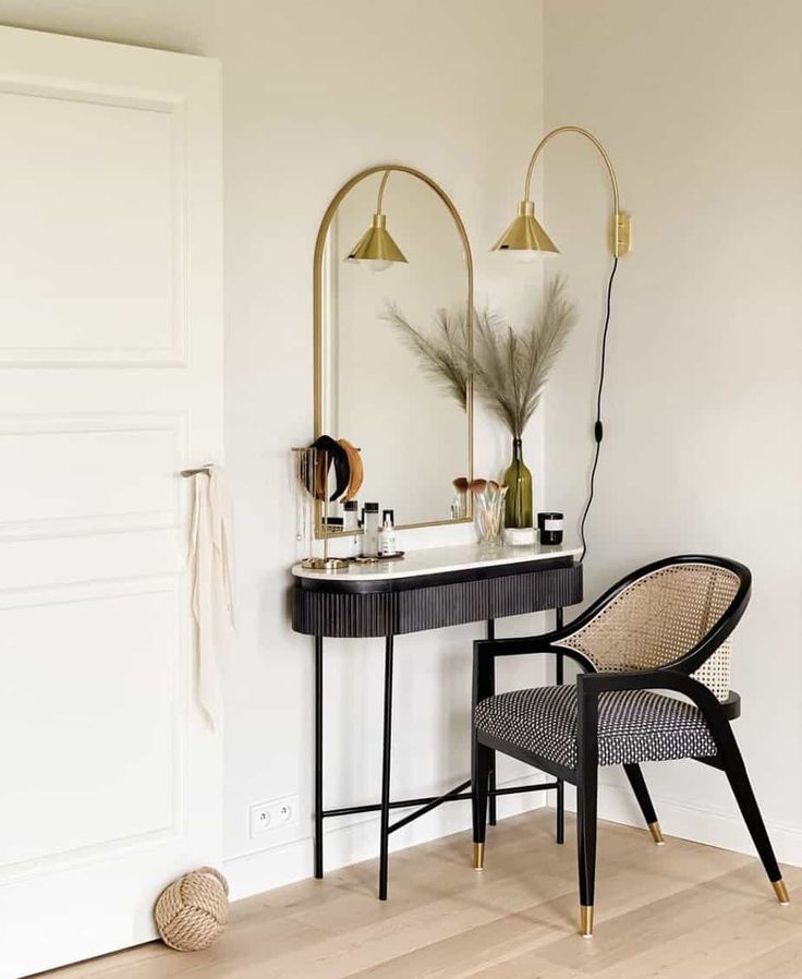 a chair sitting next to a table with a mirror on top of it and a lamp