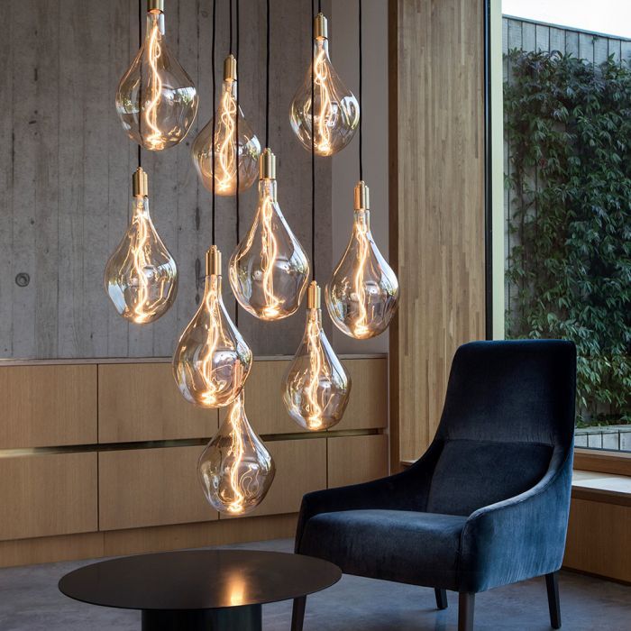 a modern chandelier hanging from the ceiling in a living room with black chairs