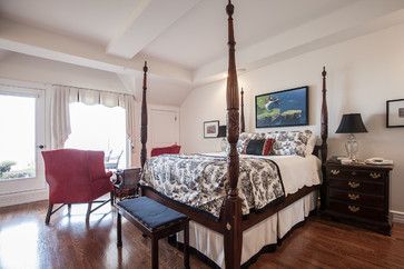 a bedroom with hardwood floors and four post bed in the center, along with two chairs