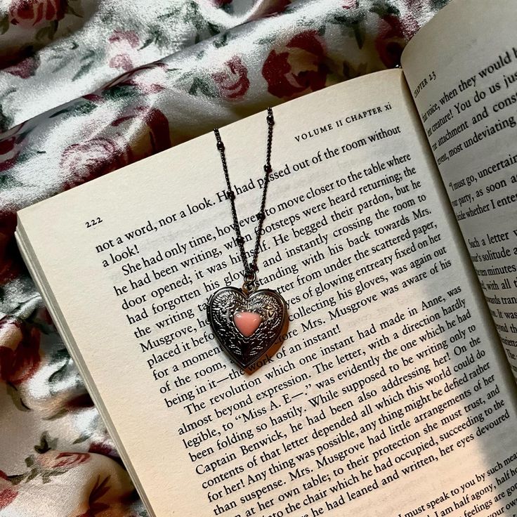 an open book with a heart shaped locke on it's cover next to a flowered blanket