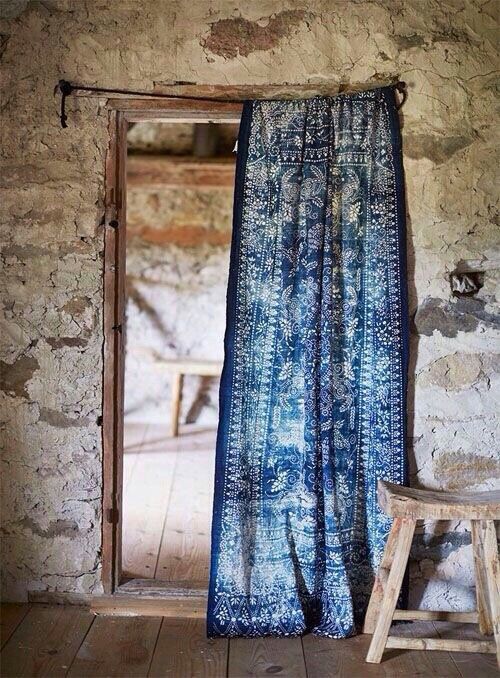 an open door with a blue curtain hanging from it's side in front of a stone wall