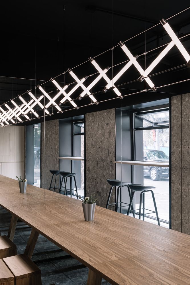 a long wooden table sitting in front of a window with barstools and stools