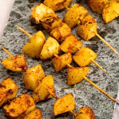 barbecue potato kebabs on a cutting board with green onions