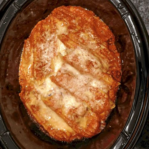 a crock pot filled with some food on top of a stove burner and covered in melted cheese