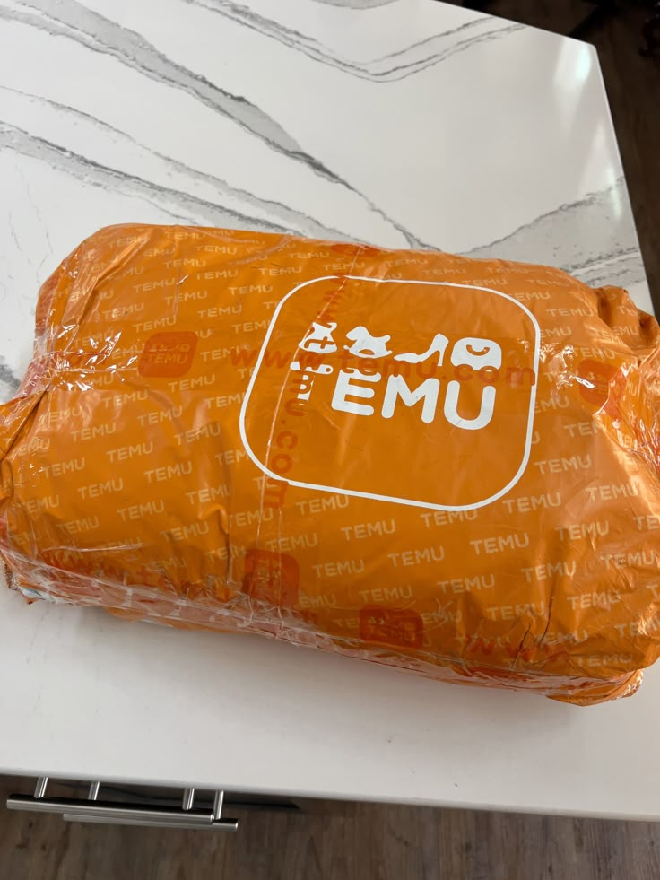 an orange bag sitting on top of a white counter next to a knife and fork